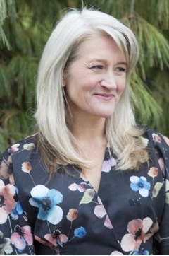 Smiling woman with blonde hair wearing a floral pattern shirt